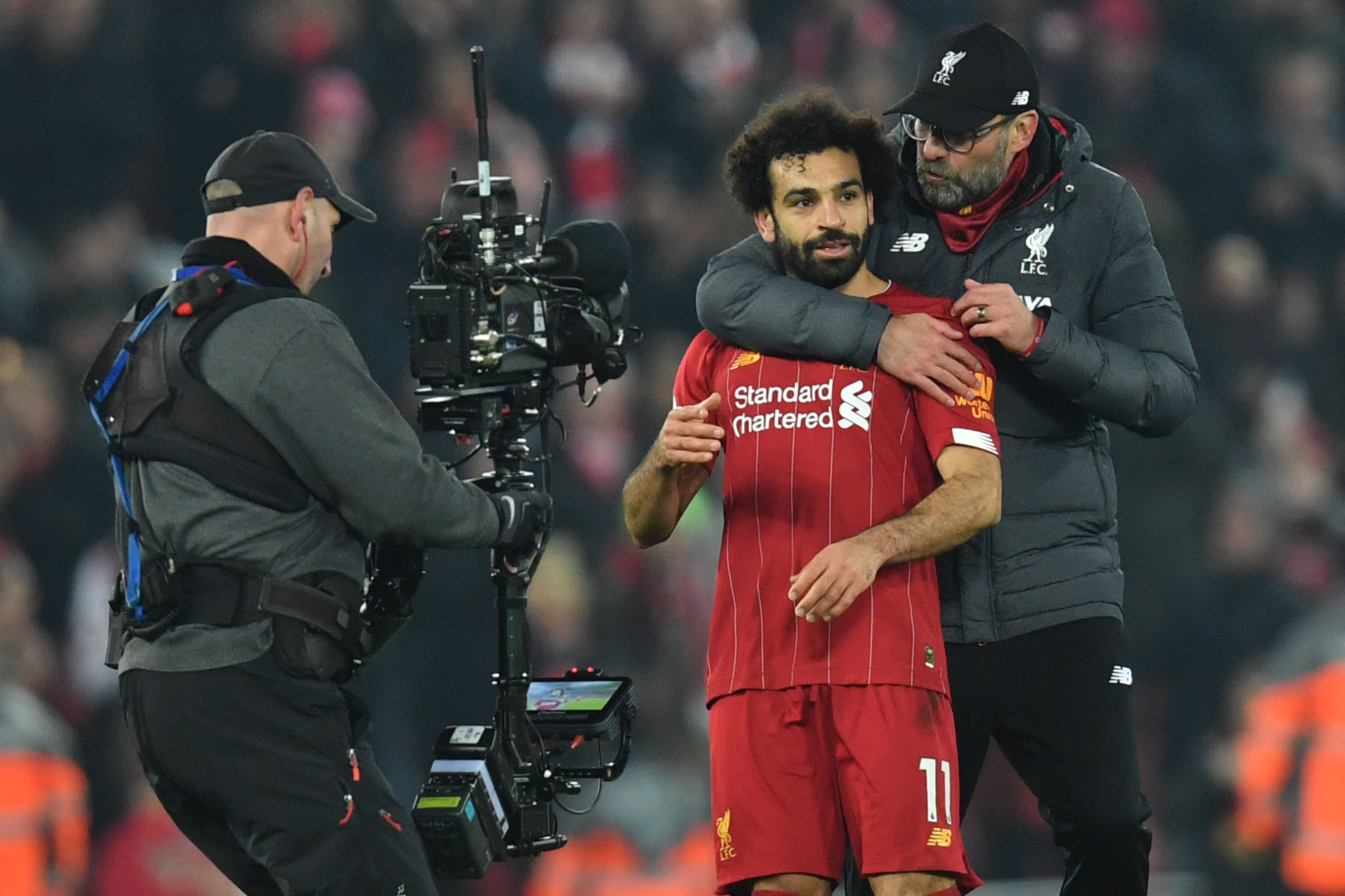 A cameraman films Liverpool's German manager Jurgen Klopp (R) embracing Liverpool's Egyptian midfielder Mohamed Salah (C) at the end of the English Premier League football match between Liverpool and Manchester United at Anfield stadium in Liverpool, nort