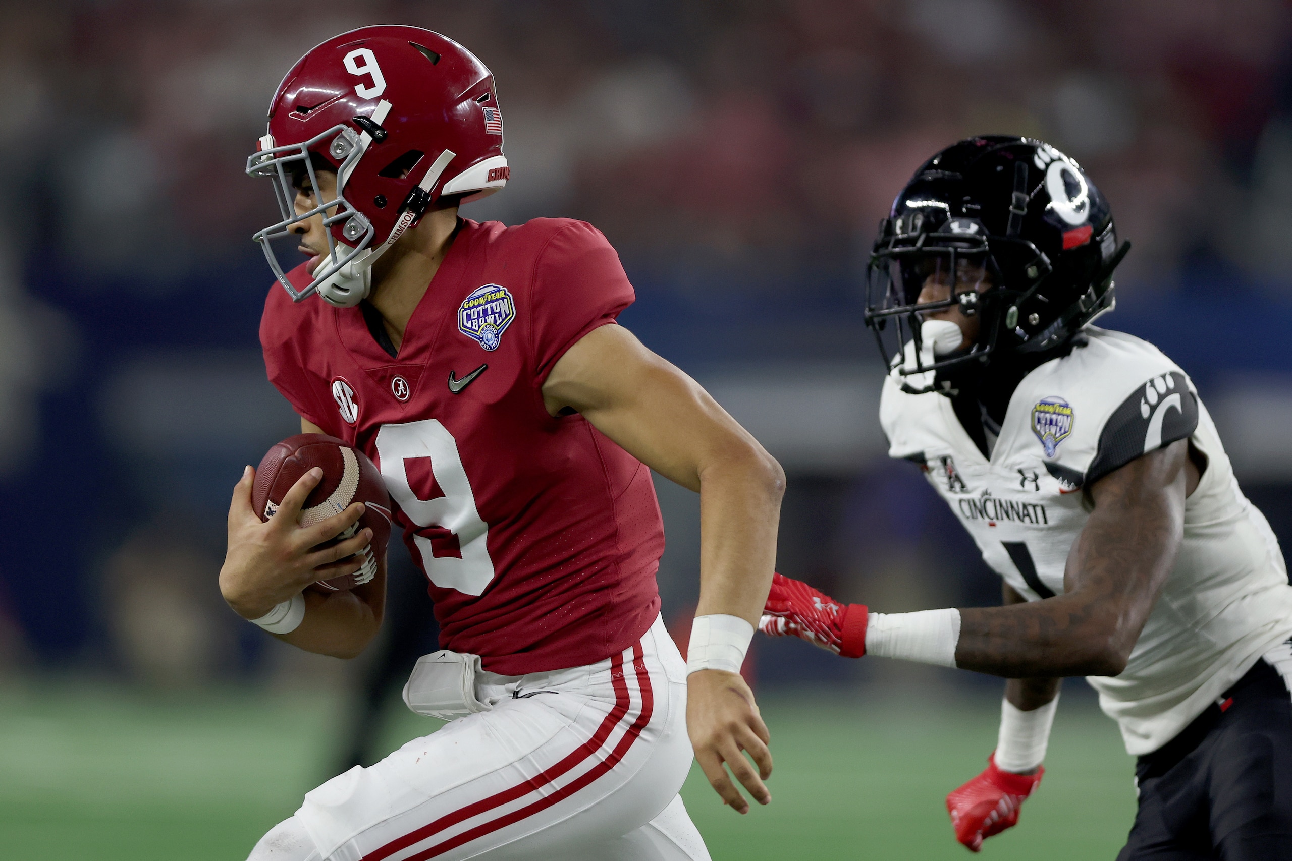 ARLINGTON, TEXAS - DECEMBER 31: Quarterback Bryce Young #9 of the Alabama Crimson Tide is chased out of the pocket by Ahmad Gardner #1 of the Cincinnati Bearcats during the Goodyear Cotton Bowl Classic for the College Football Playoff semifinal game at AT