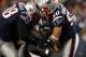 Denver Broncos quarterback Tim Tebow is taken down by two New England Patriots players.