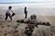 OCEANSIDE, CA - MAY 2: Wellwishers Jimmy Garcia (L) and Adam Alvarado create a cross made out of stones across the street from Junior Seau's beach home May 2, 2012 in Oceanside, California. Seau, who played for various NFL teams including the San Diego Chargers, Miami Dolphins and New England Patriots was found dead by his girlfriend in his home with a gunshot wound to his chest in an apparent suicide. (Photo by Sandy Huffaker/Getty Images)