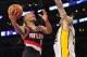 December 1, 2013; Los Angeles, CA, USA; Portland Trail Blazers point guard Damian Lillard (0) goes in for a basket against the defense of Los Angeles Lakers center Robert Sacre (50) during the first half at Staples Center. Mandatory Credit: Gary A. Vasquez-USA TODAY Sports