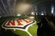FILE - In this Jan. 15, 2014 file photo, the NFL logo at midfield of MetLife Stadium is illuminated by lights on television reporters' videocameras as members of the media are given a tour under a tarp used by crews to keep the turf dry ahead of Super Bowl XLVIII in East Rutherford, N.J. As the Denver Broncos and Seattle Seahawks prep for their Feb. 2, 2014 showdown in the Super Bowl, a legal fight is playing out over the very turf installed months ago at the NFL title game's venue. Taylor Turf Installation Inc. is suing the MetLife Stadium's operators and the company that hired the suburban St. Louis company, seeking more than $292,000 that Taylor Turf claims it still is owed for hustling to install the stadium's playing surface last summer. (AP Photo/Julio Cortez, File)