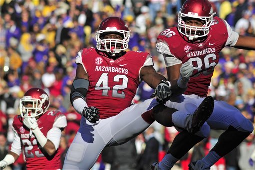 Arkansas defensive ends Chris Smith (42) and Trey Flowers (86) and cornerback Kaelon Kellybrew (23) celebrate after stopping LSU on fourth down during the first half of an NCAA college football game in Fayetteville, Ark., Friday, Nov. 23, 2012. (AP Photo/April L. Brown)