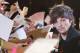One Direction member Louis Tomlinson gives his autographs to fans during an event for their film