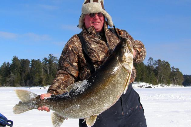 In this photo provided by Rob Scott and taken on Feb. 8, 2014, Rob Scott, of Crane Lake, Minn., poses with a 52-pound 3-ounce lake trout he caught while ice fishing on Lac la Croix on the Minnesota-Ontario border near Crane Lake, Minn. The fish was caught about 100 feet on the Canadian side of the lake. If caught in Minnesota, it easily would have been a state record. (AP Photo/Rob Scott)