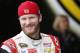 Dale Earnhardt, Jr., smiles as he stands talking with crew members in the garage during NASCAR Sprint Cup auto racing practice Saturday, March 1, 2014, in Avondale, Ariz. (AP Photo/Ross D. Franklin)