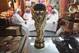 DOHA, QATAR - OCTOBER 24: Arab men sit at a shoemaker's stall with a replica of the FIFA World Cup trophy in the Souq Waqif traditional market on October 24, 2011 in Doha, Qatar. Qatar will host the 2022 FIFA World Cup football competition and is slated to tackle a variety of infrastructure projects, including the construction of new stadiums. (Photo by Sean Gallup/Getty Images)