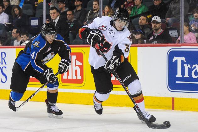 CALGARY, AB - MARCH 15: Travis Sanheim #32 of the Calgary Hitmen skates with the puck past Jaedon Descheneau #14 of the Kootenay Ice during a WHL game at Scotiabank Saddledome on March 15, 2014 in Calgary, Alberta, Canada. (Photo by Derek Leung/Getty Images)