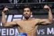 Lyoto Machida poses on the scale during a weigh-in for the UFC 175 mixed martial arts event at the Mandalay Bay, Friday, July 4, 2014, in Las Vegas. Machida is scheduled to fight Chris Weidman in a middleweight title bout on Saturday in Las Vegas. (AP Photo/John Locher)