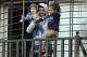 Uruguay's soccer player Luis Suarez holds his children as he greets fans from their home's balcony on the outskirts of Montevideo, Uruguay, Friday, June 27, 2014. Suarez returned to Montevideo early Friday, arriving too late to see the hundreds of Uruguay fans who had gathered the previous night to give him a hero's welcome despite his World Cup banishment. (AP Photo/Matilde Campodonico)