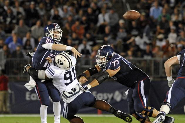 Connecticut quarterback Casey Cochran (12) is pressured by BYU defensive lineman Travis Tuiloma (91) during the first half of an NCAA college football game in East Hartford, Conn., on Friday, Aug. 29, 2014. (AP Photo/Fred Beckham)