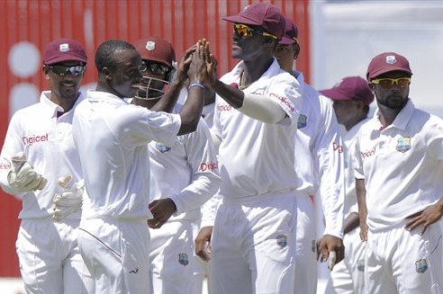 In this image released by DigicelCricket.com, West Indies' spin bowler Kemar Roach, second from left, high fives captain Darren Sammy as teammates look on after taking the wicket of New Zealand's opener BJ Watling who was caught by two runs on the opening day of their second cricket Test match in Kingston, Jamaica, Thursday, Aug. 2, 2012. (AP Photo/Digicel Cricket.com, Brooks LaTouche)