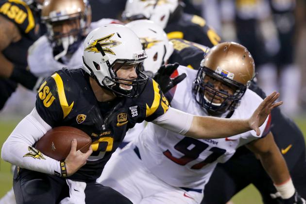 Arizona State's Taylor Kelly, left, runs with the ball as he tries to get past Arizona's Sione Tuihalamaka (91) during the second half of an NCAA college football game Saturday, Nov. 30, 2013, in Tempe, Ariz.  Arizona State defeated Arizona 58-21. (AP Photo/Ross D. Franklin)