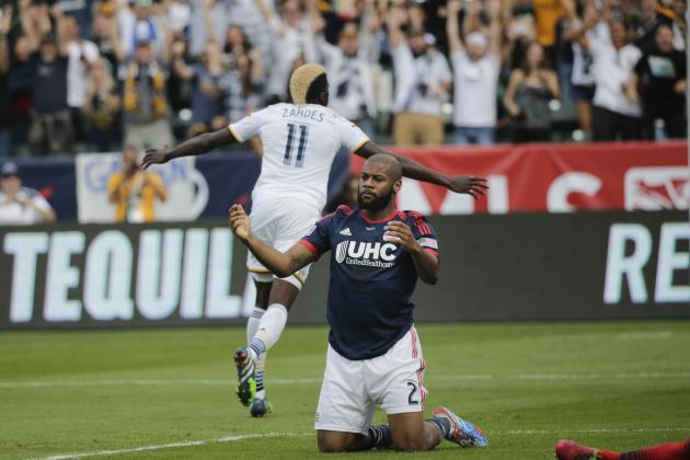New England Revolution's Andrew Farrell kneels on the field as Los Angeles Galaxy's Gyasi Zardes celebrates his goal during the second half of the MLS Cup championship soccer match Sunday, Dec. 7, 2014, in Carson, Calif. The Galaxy won 2-1 in the second extra time. (AP Photo/Jae C. Hong)