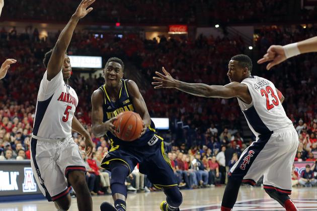 Michigan guard Caris LeVert (23) drives between Arizona forward Stanley Johnson (5) and Rondae Hollis-Jefferson (23) during the first half of an NCAA college basketball game, Saturday, Dec. 13, 2014, in Tucson, Ariz. (AP Photo/Rick Scuteri)