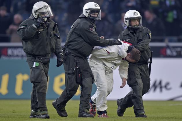 Police arrest a Cologne fan after they stormed the pitch after the German Bundesliga soccer match between Borussia Moenchengladbach and 1. FC Cologne in Moenchengladbach, Germany, Saturday, Feb. 14, 2015. Moenchengladbach defeated Cologne in overtime with 1-0. (AP Photo/Martin Meissner)
