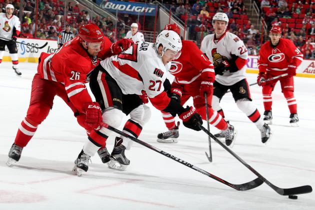 RALEIGH, NC - MARCH 17: John-Michael Liles #26 of the Carolina Hurricanes reaches for the puck around Curtis Lazar #27 of the Ottawa Senators during their NHL game at PNC Arena on March 17, 2015 in Raleigh, North Carolina. (Photo by Gregg Forwerck/NHLI via Getty Images)