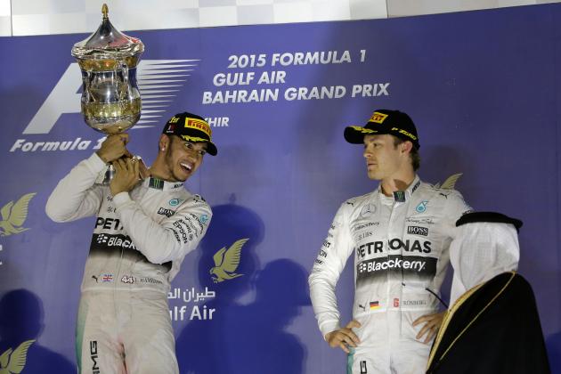 Mercedes driver Lewis Hamilton of Britain, winner, left, holds up his trophy after winning the Bahrain Formula One Grand Prix as third placed Mercedes driver Nico Rosberg of Germany, right, looks on while they stand on the podium after the Formula One Bahrain International Circuit in Sakhir, Bahrain, Sunday, April 19, 2015. (AP Photo/Hassan Ammar)