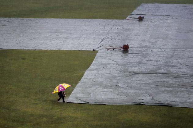 A Bangladesh’s ground staff walks with an umbrella during rain on the field to check rain covers during the fourth day of the test cricket match between Bangladesh and India in Fatullah, Bangladesh, Saturday, June 13, 2015. (AP Photo/A.M. Ahad)