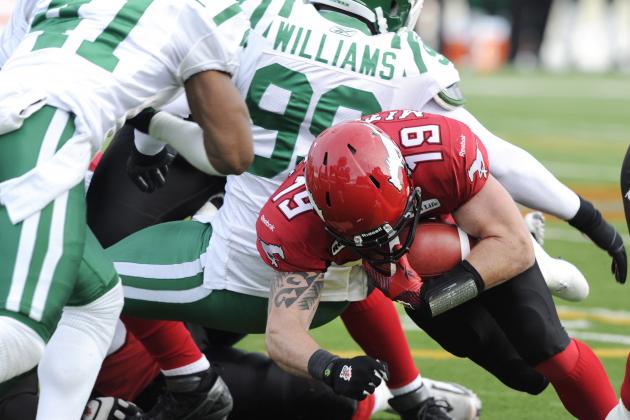 Calgary Stampeders' quarterback Bo Levi Mitchell, right, dives over the goal line for a touchdown passing Saskatchewan Roughriders' Tyron Brackenridge, left, and Shomari Williams during first half CFL Western semi-final football action in Calgary, Alberta on Sunday, Nov. 11, 2012. (AP Photo/Larry MacDougal, The Canadian Press)