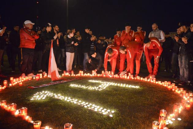 Dinamo Bucharest players light candles along with supporters after teammate Patrick Ekeng of Cameroon died after collapsing during a league match in Bucharest, Romania, Friday, May 6, 2016. Dinamo player Ekeng died at the emergency hospital after collapsing in a match, doctors said. He was 26. Cristian Pandrea, a spokesman for the Floreasca Emeregency Hospital, said doctors tried for an hour to resuscitate the Cameroon midfielder but failed. He said the cause of death was not known. (AP Photo) ROMANIA OUT