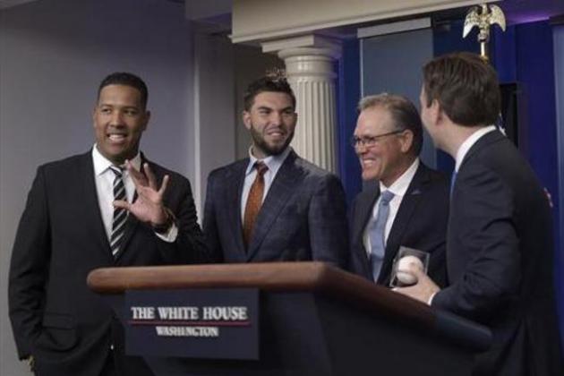 White House press secretary Josh Earnest, right, who is a big Kansas City Royals baseball team fan, holds a baseball that he was given during a surprise visit by Kansas City Royals manager Ned Yost, second from right, Salvador Perez, left, and Eric Hosmer, second from left, during the daily briefing at the White House in Washington, Thursday, July 21, 2016. (AP Photo/Susan Walsh)