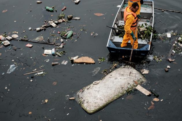 Environment Institute of Rio de Janeiro State (INEA) staffers collect a bed mattress as the tide moves away from the 'eco-barrier' set up to catch floating debris before they enter Guanabara Bay at the mouth of the Meriti river, in Duque de Caxias, next to Rio de Janeiro, Brazil, on July 20, 2016. / AFP / YASUYOSHI CHIBA (Photo credit should read YASUYOSHI CHIBA/AFP/Getty Images)
