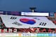 South Korea fans hold a giant national flag during the U-20 World Cup round of 16 football match between South Korea and Portugal in Cheonan on May 30, 2017. / AFP PHOTO / KIM Doo-Ho (Photo credit should read KIM DOO-HO/AFP/Getty Images)