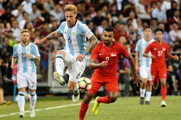 Lucas Biglia (L) of Argentina competes for the ball with Muhammad Nazrul Bin Ahmad Nazari of Singapore (R) during their international friendly football match at the national stadium in Singapore on June 13, 2017. / AFP PHOTO / ROSLAN RAHMAN        (Photo credit should read ROSLAN RAHMAN/AFP/Getty Images)