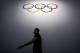 A man walks under the Olympic logo during the 128th International Olympic Committee (IOC) session in Kuala Lumpur, Malaysia on Sunday, Aug. 2, 2015. (AP Photo/Joshua Paul)