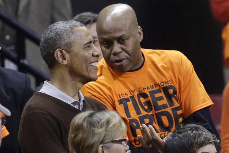 President Barack Obama chats with his brother-in-law Craig Robinson before an NCAA college basketball game between Princeton and Green Bay in the first round of the NCAA tournament, Saturday, March 21, 2015, in College Park, Md. Robinson's daughter is Princeton forward Leslie Robinson. (AP Photo/Patrick Semansky)