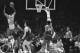 The Lakers' Tommy Hawkins fries a jump shot against the Boston Celtics in their NBA playoff game at Los Angeles May 2, 1968. At right are Bill Russell (6) and Bailey Howell. Hawkins hit several in the opening minutes. (AP Photo/HF)