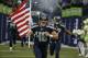 Seattle Seahawks long snapper and military veteran Nate Boyer runs out of the tunnel with a U.S. flag at the start of a preseason NFL football game against the Denver Broncos, Friday, Aug. 14, 2015, in Seattle. (AP Photo/Elaine Thompson)