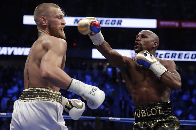 Floyd Mayweather Jr. hits Conor McGregor in a super welterweight boxing match Saturday, Aug. 26, 2017, in Las Vegas. (AP Photo/Isaac Brekken)