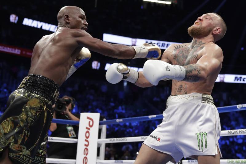 Floyd Mayweather Jr. hits Conor McGregor in a super welterweight boxing match Saturday, Aug. 26, 2017, in Las Vegas. (AP Photo/Isaac Brekken)