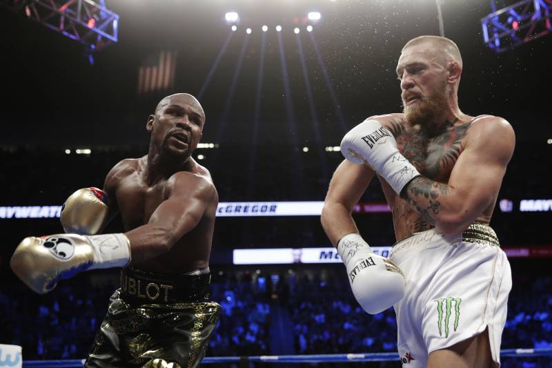Floyd Mayweather Jr., left, swings at Conor McGregor in a super welterweight boxing match Saturday, Aug. 26, 2017, in Las Vegas. (AP Photo/Isaac Brekken)
