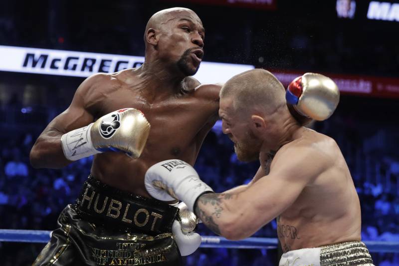 Floyd Mayweather Jr., left, fights Conor McGregor in a super welterweight boxing match Saturday, Aug. 26, 2017, in Las Vegas. (AP Photo/Isaac Brekken)