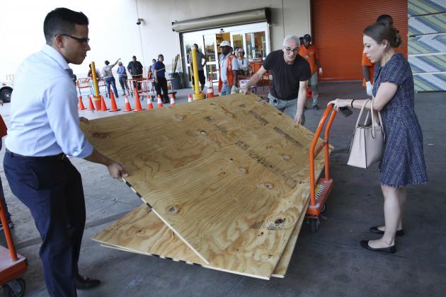 Carla Perroni Aguilera of Miami Beach, Fla., holds a cart as her husband Ronald Aguilera and her father Joe Perroni load sheets of plywood at The Home Depot store in North Miami, Fla., Wednesday, Sept. 6, 2017. Florida residents are preparing for the possible landfall of Hurricane Irma, the most powerful Atlantic Ocean hurricane in recorded history. (AP Photo/Marta Lavandier)