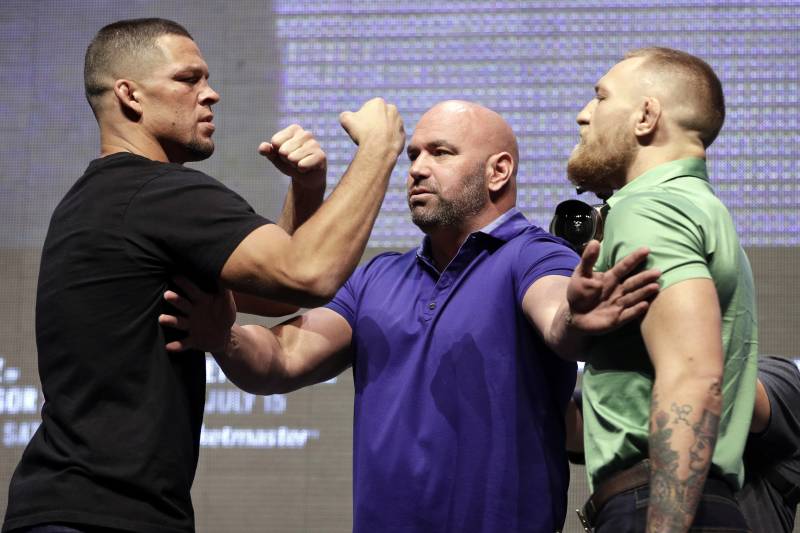 FILE - In this July 7, 2016, file photo, Dana White, center, stands between Nate Diaz, left, and Conor McGregor during a news conference in Las Vegas for UFC 202. McGregor is being fined $150,000 by the Nevada Athletic Commission for a profanity-laced bottle-throwing fracas that erupted during a pre-fight news conference with rival Nate Diaz in August in Las Vegas. (AP Photo/John Locher, File)