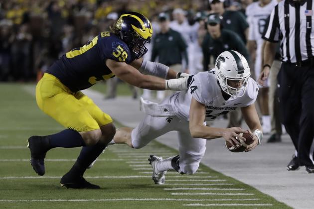 Michigan State quarterback Brian Lewerke (14) stretches for yardage as he is pushed out of bounds by Michigan linebacker Noah Furbush (59) during the first half of an NCAA college football game, Saturday, Oct. 7, 2017, in Ann Arbor, Mich. (AP Photo/Carlos Osorio)