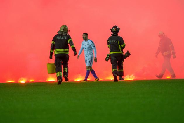Firemen run on the pitch to take care of flares thrown by Bosnia fans during the FIFA World Cup 2018 qualification football match between Estonia and Bosnia in Tallinn, Estonia on October 10, 2017. / AFP PHOTO / RAIGO PAJULA (Photo credit should read RAIGO PAJULA/AFP/Getty Images)