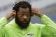 Seattle Seahawks defensive end Michael Bennett wears headphones as he stands on the field during warmups before an NFL football game against the Houston Texans, Sunday, Oct. 29, 2017, in Seattle. (AP Photo/Elaine Thompson)