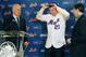 New York Mets general manager Sandy Alderson, left, and Mets owner Jeff Wilpon, right, watch as newly-signed Mets' third baseman Todd Frazier dons a Mets cap and jersey during a press conference, Wednesday, Feb. 7, 2018, at CitiField in New York. Frazier reportedly signed a two-year deal, finalized on Wednesday. The contract calls for Frazier to be paid $8 million this year and $9 million in 2019. (AP Photo/Kathy Willens)