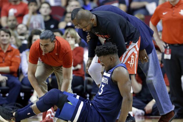 Minnesota Timberwolves guard Jimmy Butler (23) reacts to a knee injury on the court as Houston Rockets guard Chris Paul (3) and team trainers hover over him during the second half of an NBA basketball game Friday, Feb. 23, 2018, in Houston. (AP Photo/Michael Wyke)