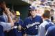 Milwaukee Brewers' Christian Yelich gets high-fives from teammates after scoring a run against the Cincinnati Reds during the third inning of a spring training baseball game Friday, March 16, 2018, in Goodyear, Ariz. (AP Photo/Ross D. Franklin)