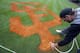 Grounds crew member Josh Warstler paints the San Francisco Giants logo on stadium grass after the Giants played the Arizona Diamondbacks in a spring training baseball game Sunday, March 2, 2014, in Scottsdale, Ariz. (AP Photo/Gregory Bull)