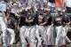Oregon State's Steven Kwan (4) is congratulated by teammates after he scored against North Carolina on a one-run triple by Trevor Larnach in the first inning of an NCAA College World Series baseball game in Omaha, Neb., Saturday, June 16, 2018. (AP Photo/Nati Harnik)