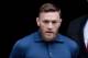 Ultimate fighting star Conor McGregor is led by an official onto an unmarked vehicle while leaving the 78th Precinct of the New York Police Department, Friday, April 6, 2018, in the Brooklyn borough of New York. McGregor is facing criminal charges in the wake of a backstage melee he allegedly instigated that has forced the removal of three fights from UFC's biggest card of the year. Video footage appears to show the promotion's most bankable star throwing a hand truck at a bus full of fighters after a Thursday news conference for UFC 223 at Brooklyn's Barclays Center. (AP Photo/Julio Cortez)