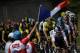 A spectator waves the French flag as Great Britain's Geraint Thomas (C-L), wearing the overall leader's yellow jersey, rides in the pack during the 15th stage of the 105th edition of the Tour de France cycling race, between Millau and Carcassonne on July 22, 2018. (Photo by Marco BERTORELLO / AFP) (Photo credit should read MARCO BERTORELLO/AFP/Getty Images)