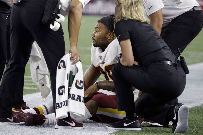 Washington Redskins running back Derrius Guice, center, receives attention on the field after an injury during the first half of a preseason NFL football game against the New England Patriots, Thursday, Aug. 9, 2018, in Foxborough, Mass. (AP Photo/Steven Senne)
